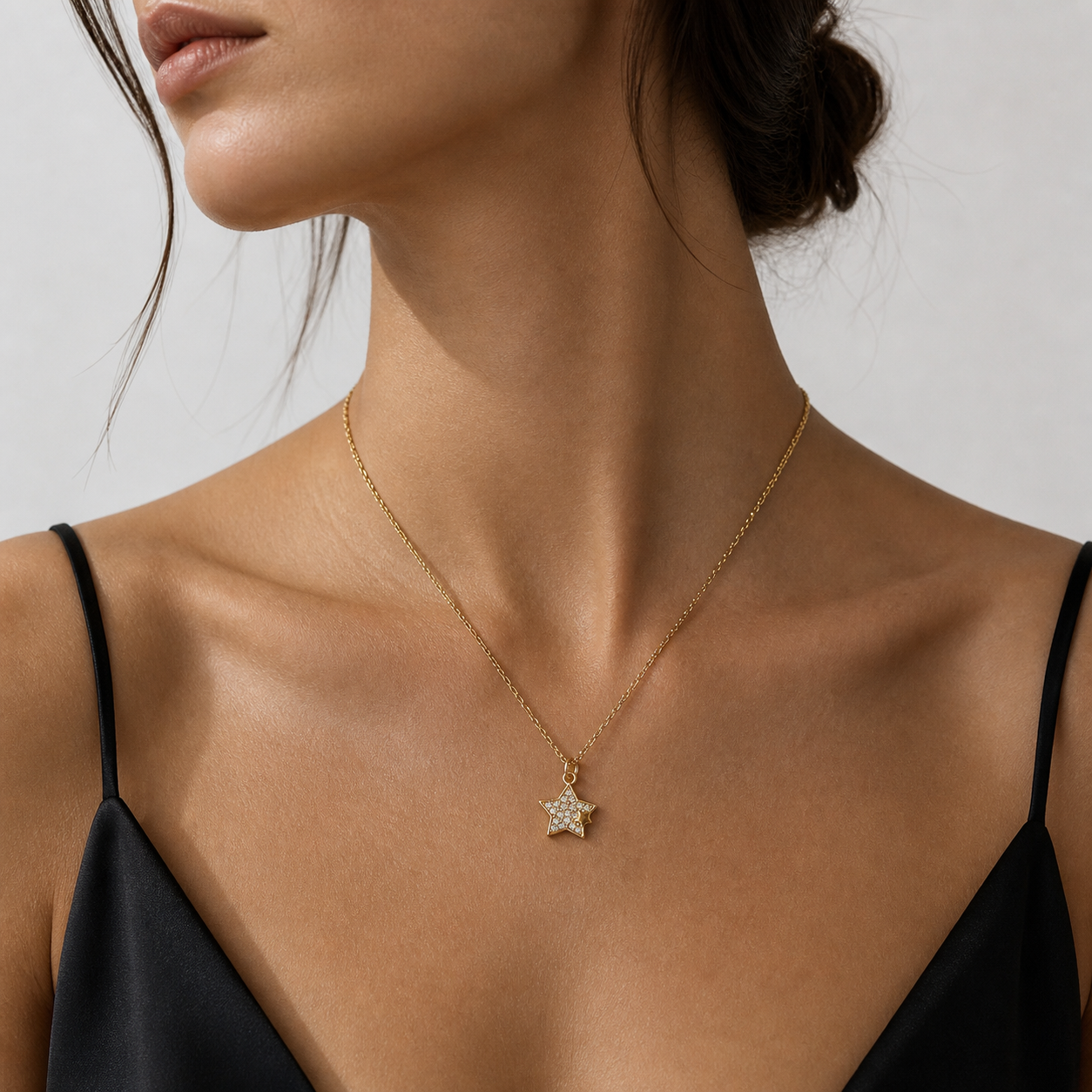Close-up of a woman wearing a gold necklace with a star pendant on a neutral background