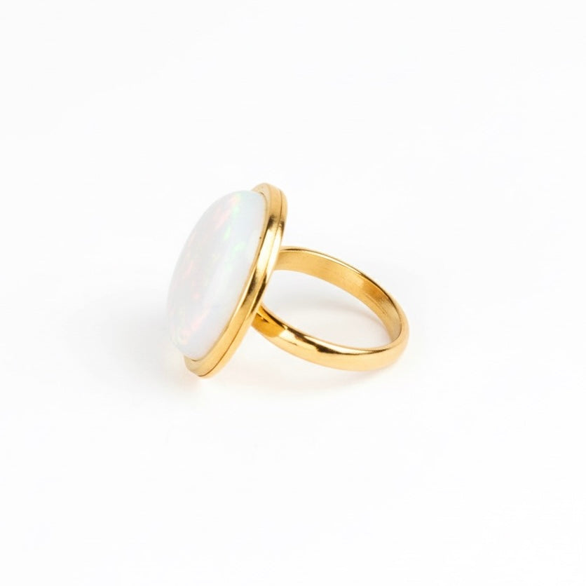 Gold ring with a large white stone on a white background