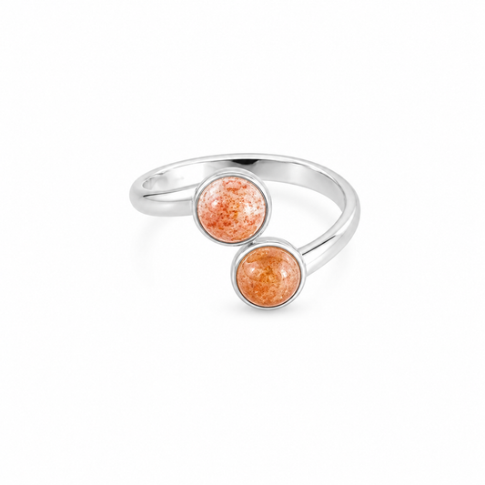 Silver ring with two orange gemstones on a white background