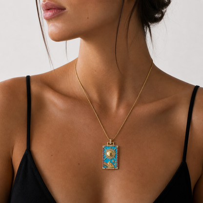 Woman wearing a gold necklace with a blue pendant against a neutral background