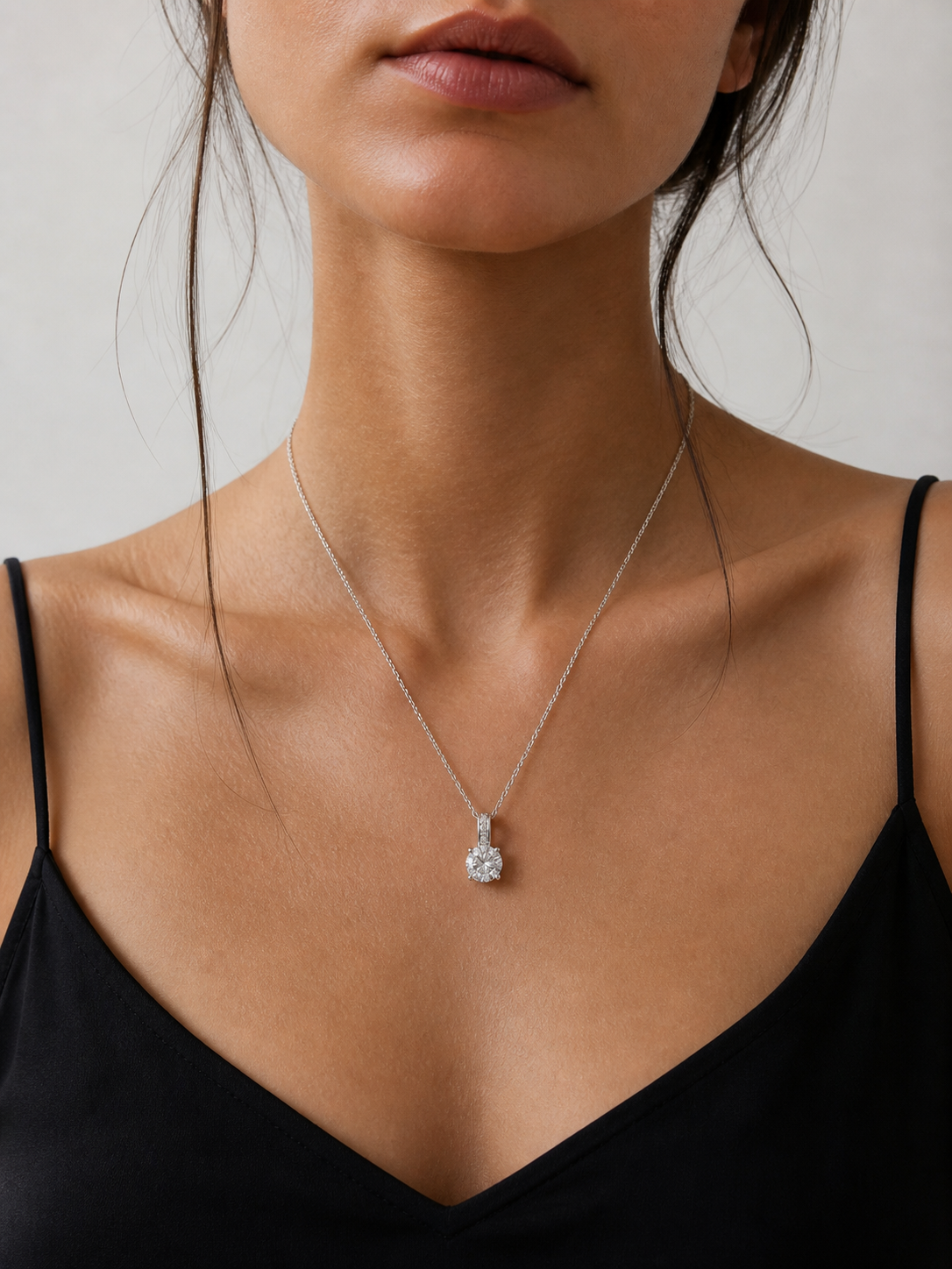 Necklace with a diamond pendant worn by a person against a neutral background