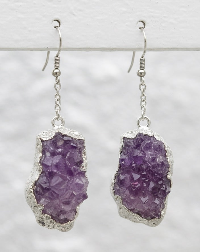 Purple amethyst geode earrings with silver settings on a light gray background