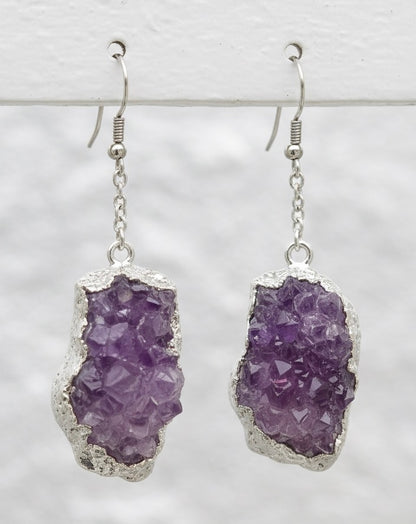 Purple amethyst geode earrings with silver settings on a light gray background