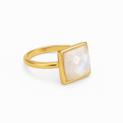 Gold ring with a square, light-colored stone on a white background