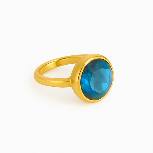 Gold ring with a blue gemstone on a white background