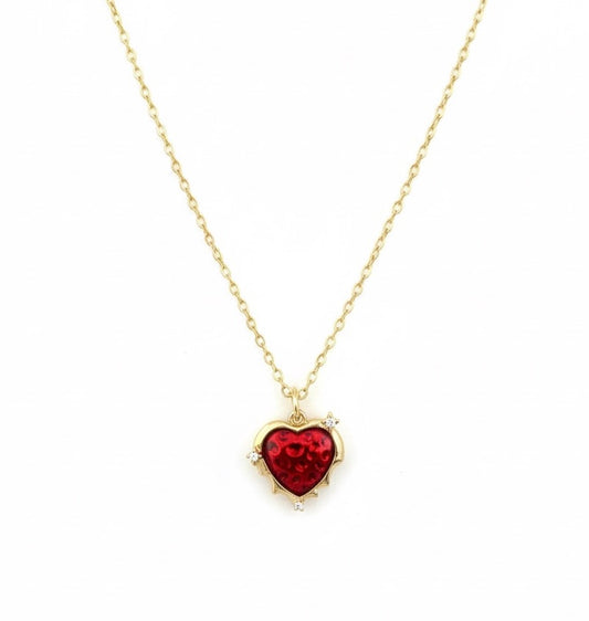 Heart-shaped red gemstone necklace on a gold chain against a white background
