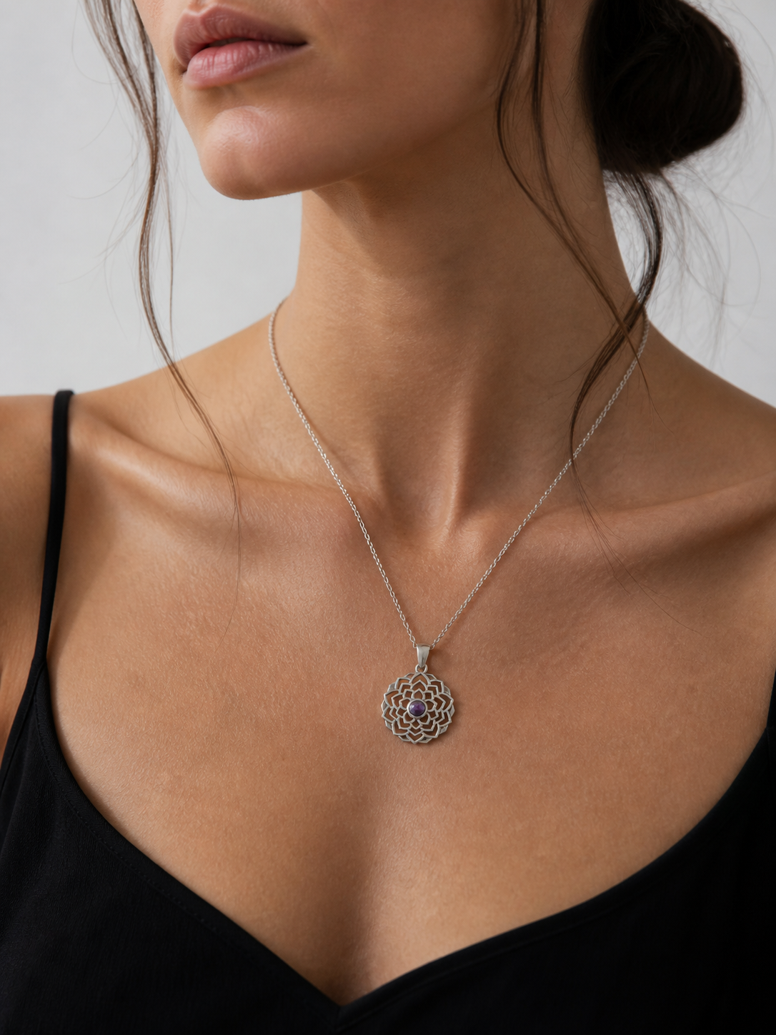 Necklace with a pendant worn by a person against a neutral background
