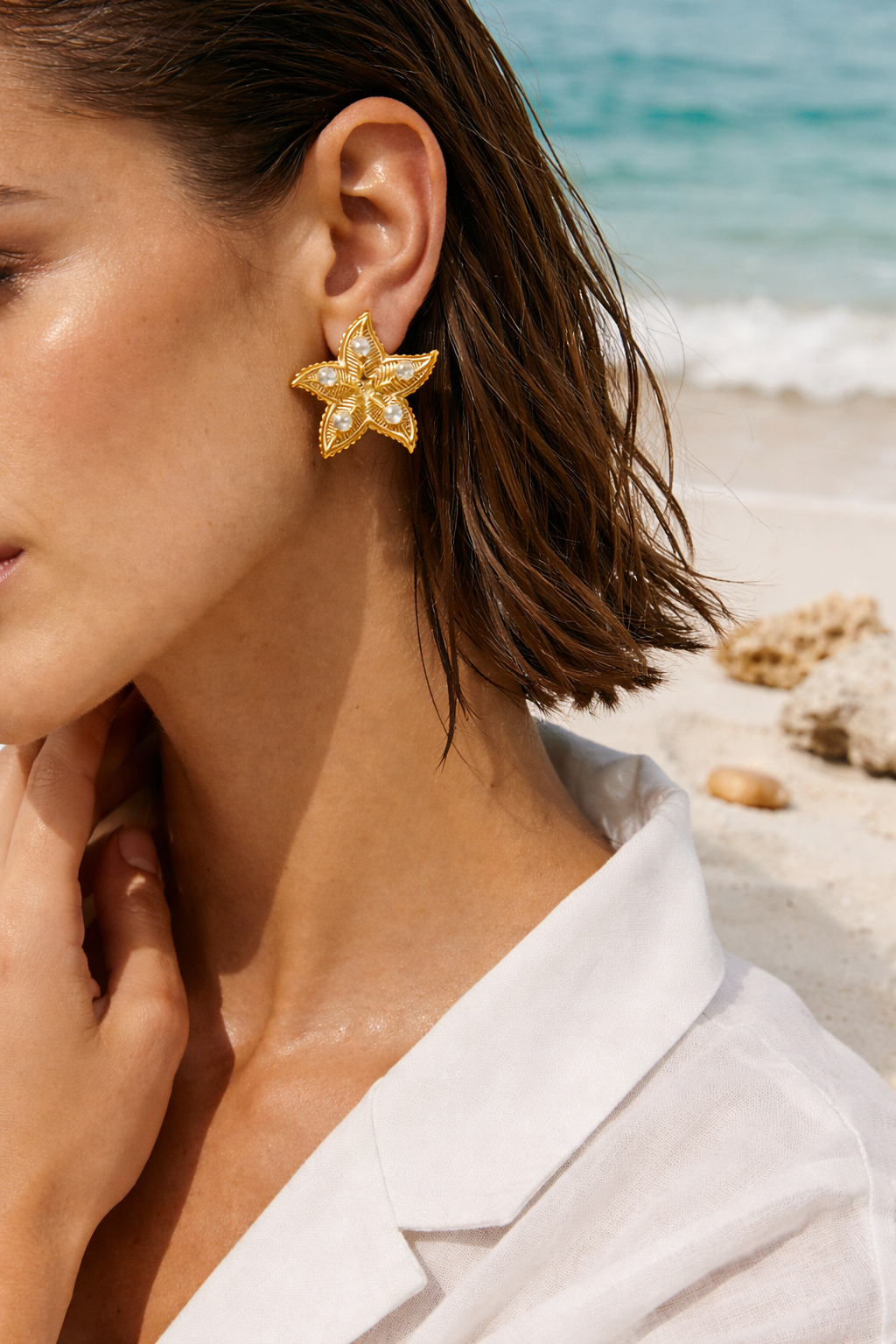 Woman wearing gold star-shaped earrings with a beach background