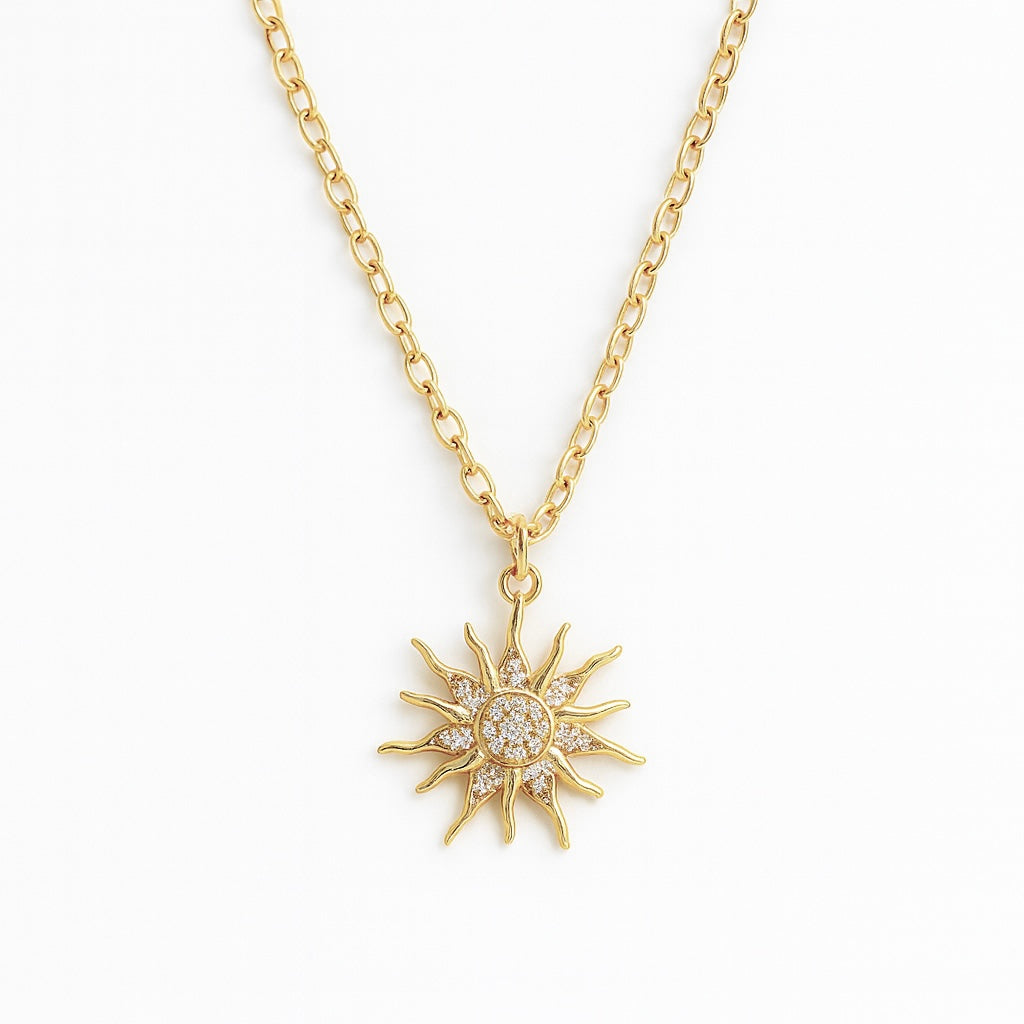 Gold sun-shaped pendant necklace on a white background