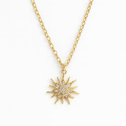 Gold sun-shaped pendant necklace on a white background