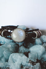 Cargar imagen en el visor de la galería, &quot;Boho-inspired Rainbow Moonstone Beaded Stack Bracelet featuring a 20mm AAA-grade moonstone on an adjustable braided bracelet with beads and faux leather.&quot;
