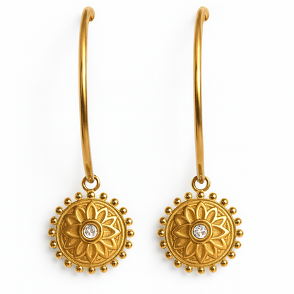Gold earrings with floral designs and clear stones on a white background