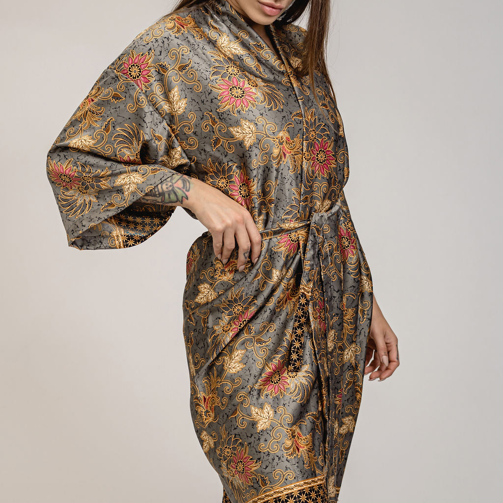 Woman wearing a patterned dress with floral designs on a plain background